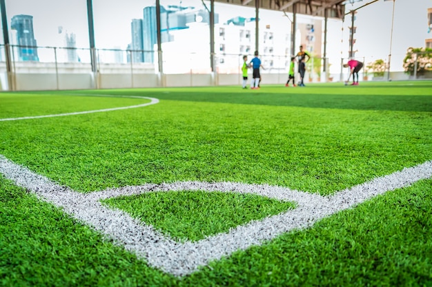 Línea blanca de la esquina del fútbol en la hierba verde del artefacto del campo de fútbol de interior.