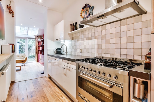 Línea de cocina con gabinetes blancos y mostrador negro con estufa de gas grande en apartamento moderno