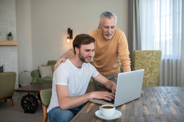 En línea. Dos hombres mirando algo en una computadora portátil y mirando involucrado