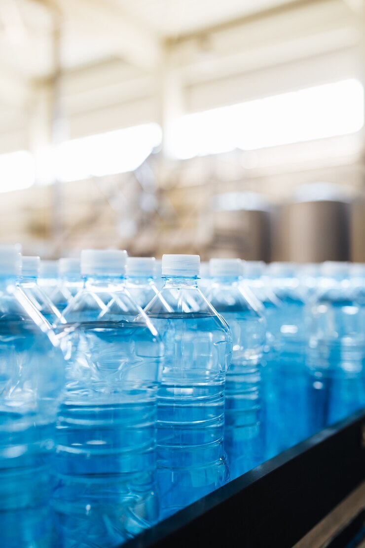 Foto línea de embotellado de agua para procesar y embotellar agua pura de manantial en botellas azules