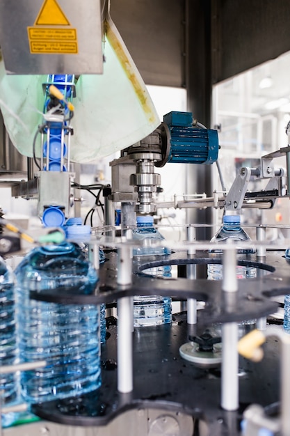 Foto línea de embotellado de agua para procesar y embotellar agua pura de manantial en botellas azules
