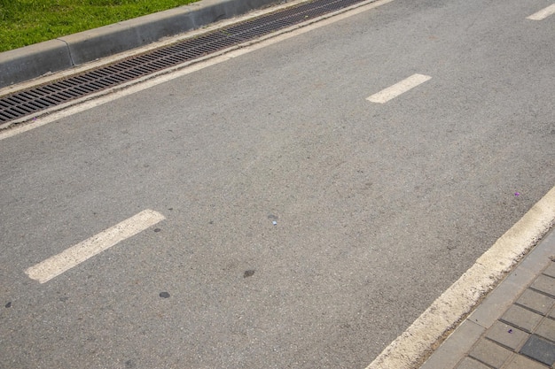 Una línea de marcado de carril intermitente y la dirección del tráfico en una carretera asfaltada