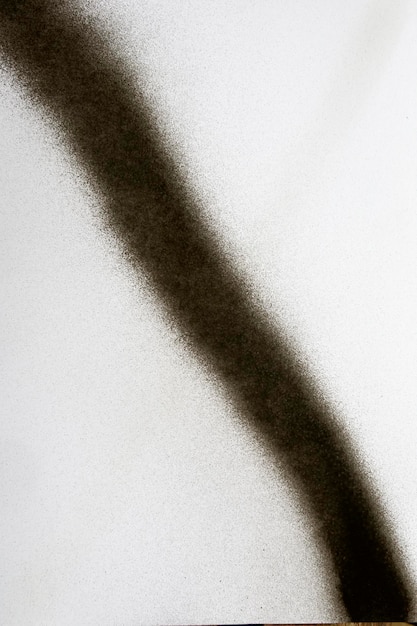 Línea negra diagonal de pintura en aerosol sobre papel blanco