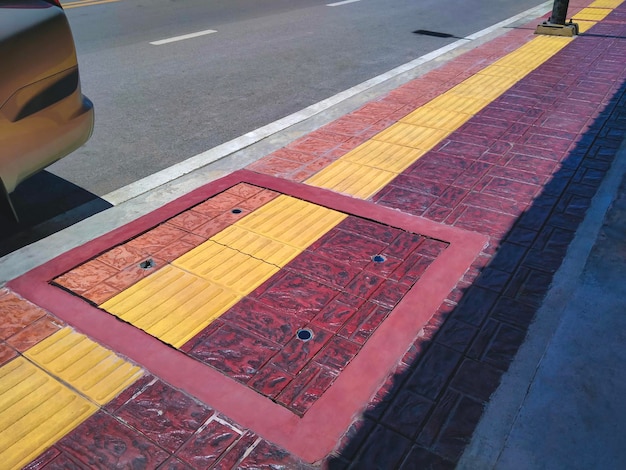 Línea de pavimentación táctil amarilla con suelo de baldosas marrones para ciegos y deficientes visuales en la acera