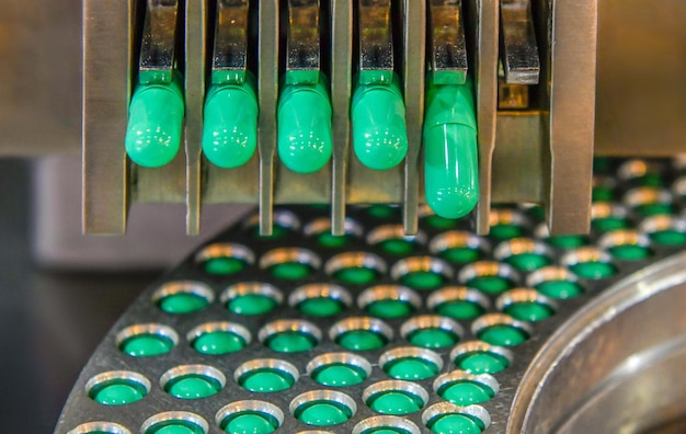 Foto línea de producción de píldoras de medicina cápsula verde, concepto farmacéutico industrial.