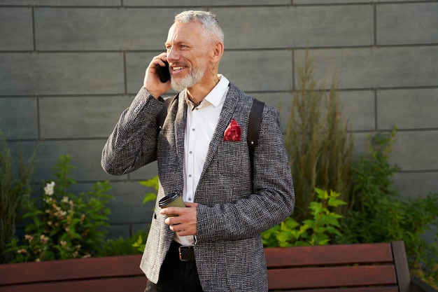 En la línea retrato de feliz exitoso hombre de negocios de mediana edad en elegante traje sonriendo mientras