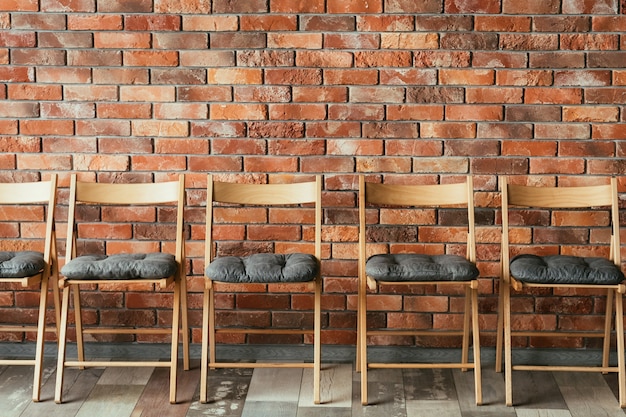 Línea de sillas vacías en el desván de la pared de ladrillo. asiento libre. concepto de sala de espera o sesión de entrevista de trabajo. competencia rivalidad y promoción.