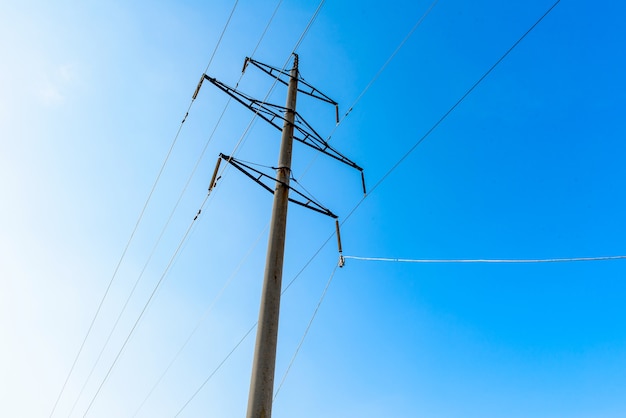 Línea de transmisión de alta tensión con soportes de hormigón, cielo azul. Sistema eléctrico