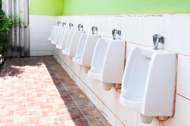 Línea de urinarios de porcelana blanca en baños públicos baños sucios al aire libre