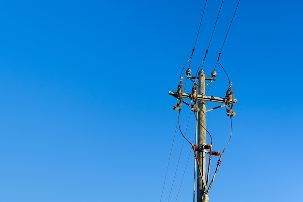 Líneas de cielo de energía eléctrica y conexiones en un poste de madera. Poste de electricidad de madera contra el cielo azul