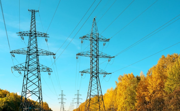 Líneas eléctricas y torres contra un fondo de cielo azul en otoño