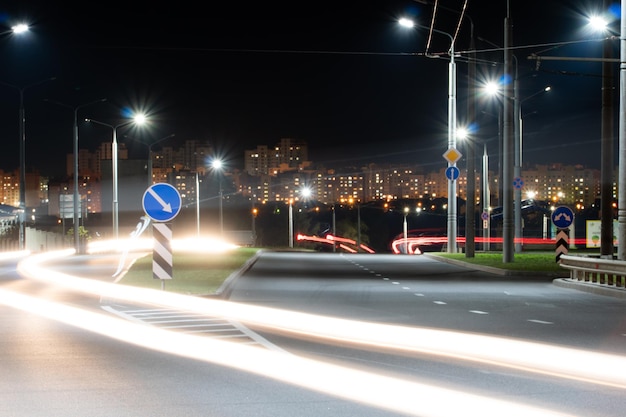 Líneas de luz de la ciudad nocturna de los automóviles en la carretera con movimiento borroso Vista de la calle de la ciudad moderna por la noche Mucha luz de los faros de los automóviles que anuncian pancartas y luces nocturnas