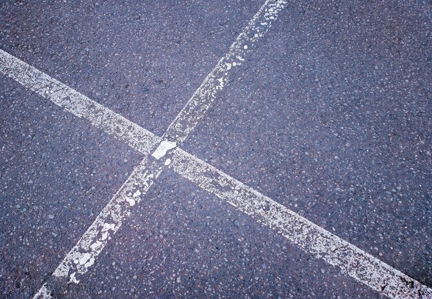 Líneas de marcado blancas cruzadas sobre el fondo de una carretera antigua