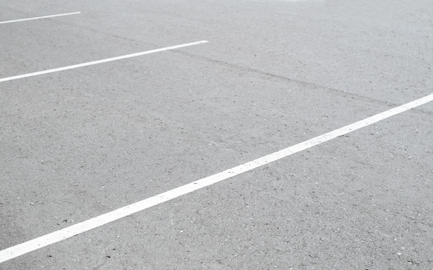 Líneas de marcado blanco sobre asfalto en un estacionamiento vacío al aire libre