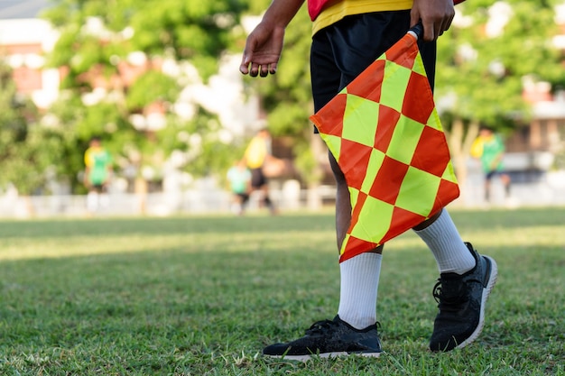 Lineman o árbitro asistente de fútbol o fútbol con bandera en el campo de fútbol