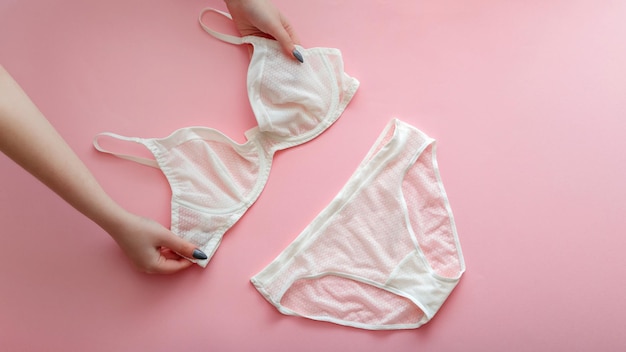 Lingerie de renda branca em mãos femininas conjunto de lingerie translúcida sexy calcinha branca e sutiã rosa