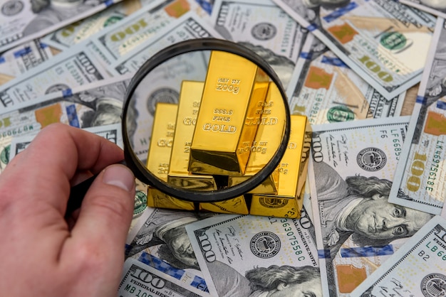 Lingote, ouro ou lingote em cédula de dólar americano com lupa
