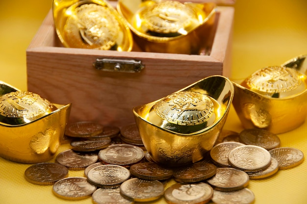 Lingotes de ouro chineses e moedas no baú do tesouro no conceito de riqueza e prosperidade de fundo amarelo