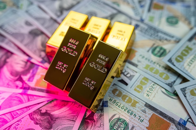 Lingotes de oro en billetes de dólar americano closeup aislado sobre fondo liso