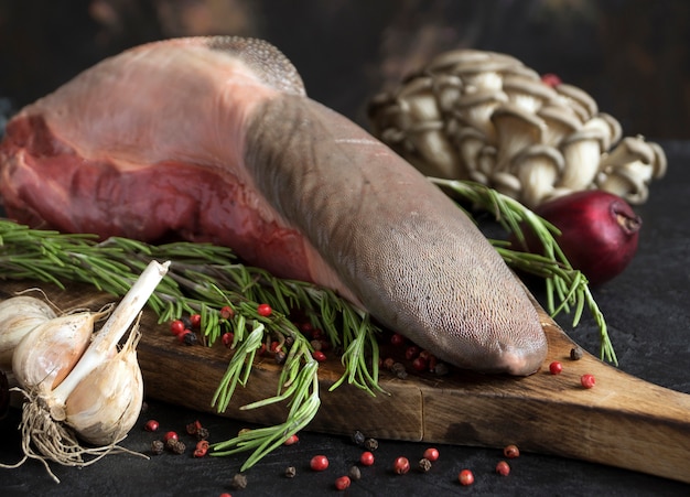 Foto língua de carne crua em uma tábua de cortar. com especiarias