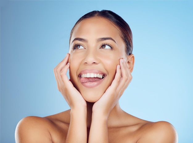 Língua de mulher para fora e maquiagem em estúdio para cuidados com a pele e cuidados com a beleza no espaço de fundo azul Emoji headshot e modelo de menina relaxam em pele cosmética de luxo e bem-estar e tratamento natural