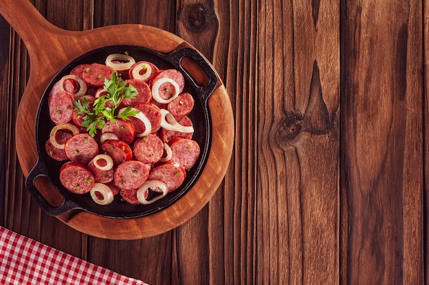 Foto linguiça calabresa defumada fatiada com cebola - vista superior do aperitivo brasileiro com cópia espacial