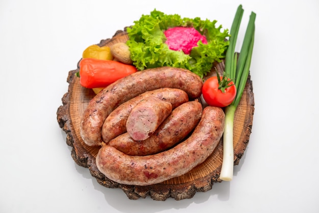 Foto linguiça caseira com legumes em uma tábua de madeira