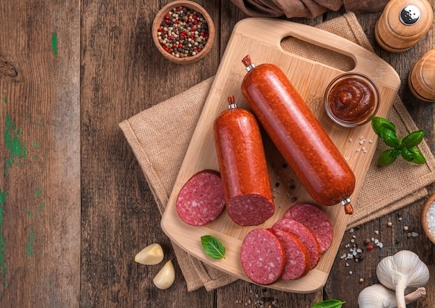 Linguiça defumada com especiarias e manjericão fresco em um fundo de madeira. Vista superior, copie o espaço.