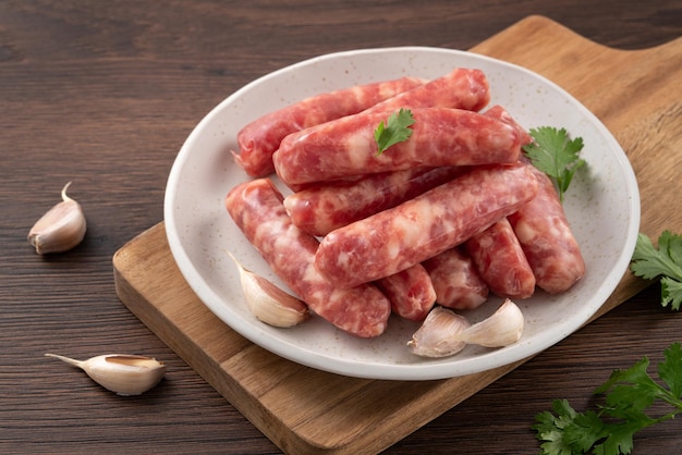 Linguiça taiwanesa crua com sabor de alho em um prato sobre fundo de mesa de madeira