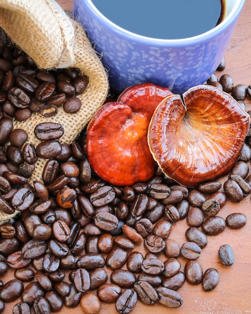 Foto lingzhi-pilz, reishi-pilz-tasse kaffee und kaffeebohnen auf hölzerner tabelle