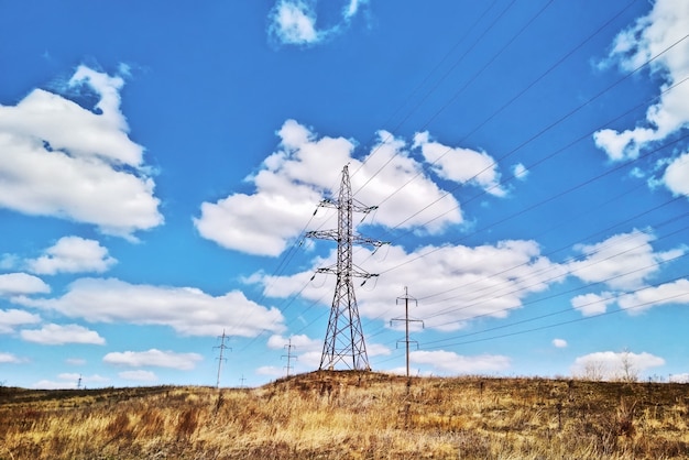 Linha aérea de energia em dia de verão no campo no fundo do céu azul