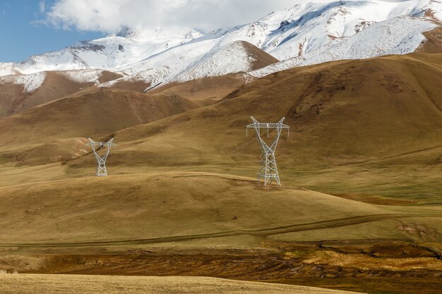 Linha de alta tensão no Quirguistão. Postes de eletricidade de tensão nas montanhas.