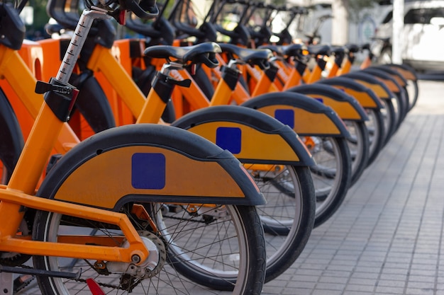 Linha de bicicletas laranja na estação de estacionamento da rua Aluguel de bicicletas públicas no conceito de cidade urbana