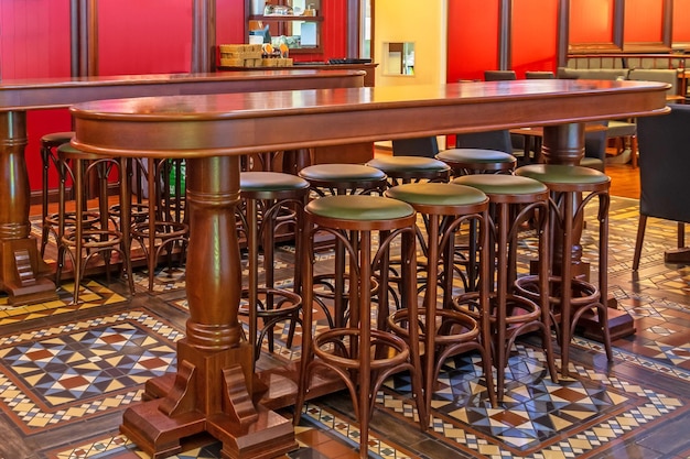 Linha de cadeiras altas de madeira em um bar em frente a uma mesa em um pub