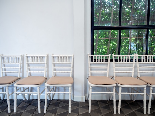 Linha de cadeiras de madeira vintage branco com almofadas.
