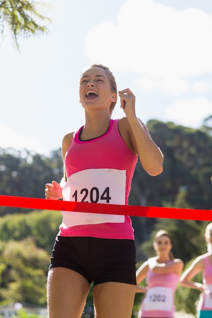 Foto linha de chegada alegre do cruzamento do atleta do vencedor