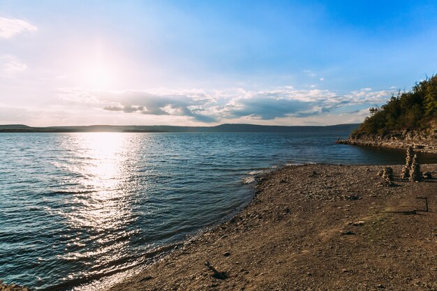 Linha de costa do lago no pôr do sol fantástico. Paisagem da costa vazia em uma baía preenchida com luz solar
