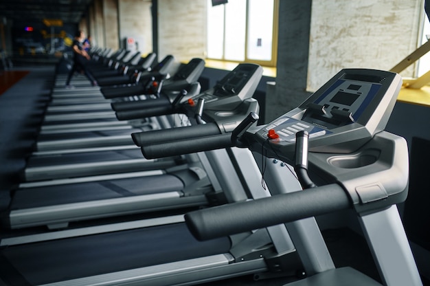 Linha de esteiras no ginásio, máquina em execução, ninguém. equipamento para treinamento cardiovascular e cuidados de saúde, interior do clube desportivo