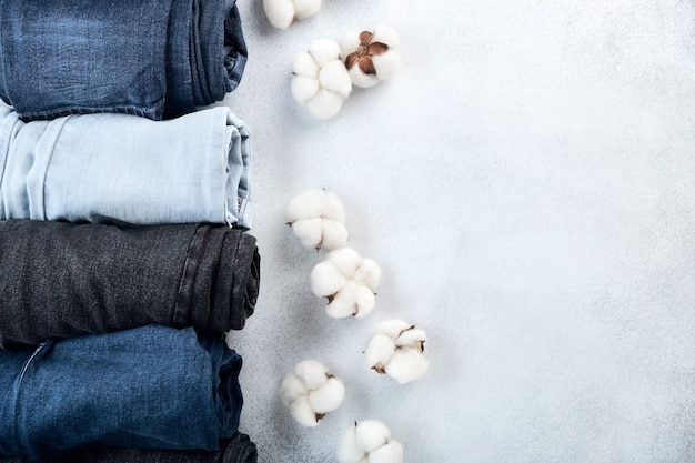 Linha de jeans enrolados e flores de algodão em fundo claro