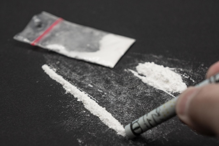 Foto linha de pó branco, anfetamina e cocaína. uma pessoa que toma uma dose de drogas.