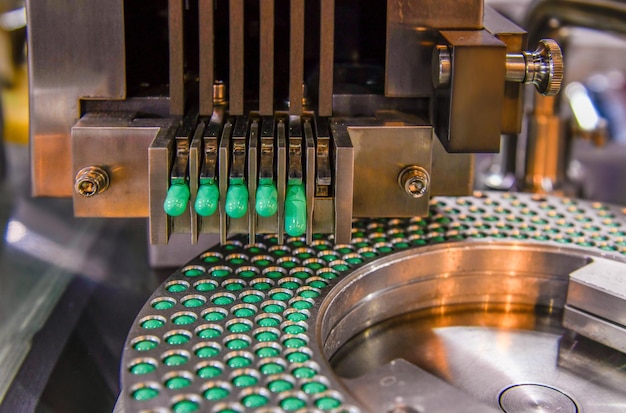 Foto linha de produção do comprimido do medicamento cápsula verde, conceito farmacêutico industrial.