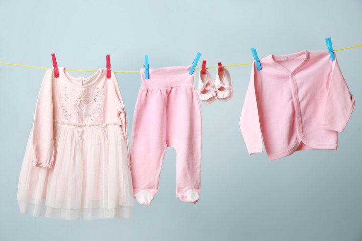 Foto linha de roupa com roupas de bebê penduradas em fundo cinzento