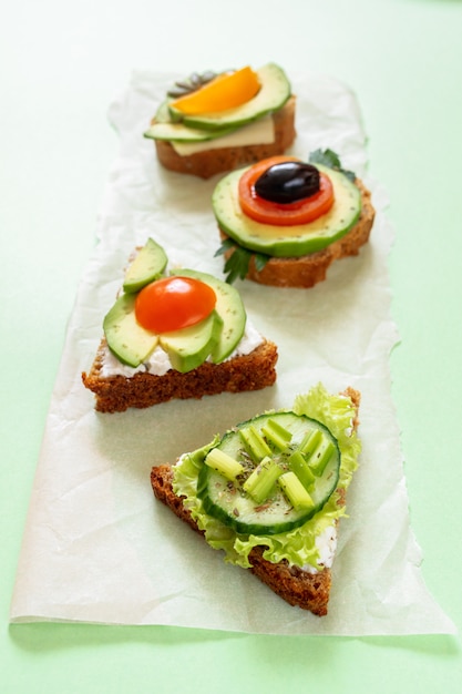 Linha de sanduíches vegetarianos sobre fundo verde. Foco seletivo.