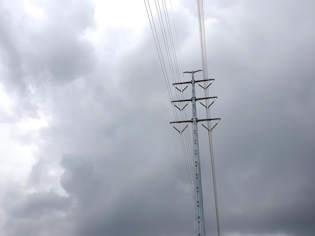 Linha de transmissão elétrica de alta tensão em nuvens nimbus nos fundos do céu.