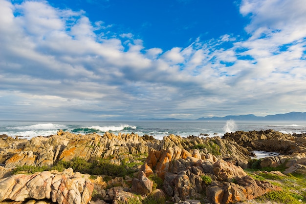 Linha rochosa da costa no oceano em de kelders, áfrica do sul, famosa para a observação da baleia. estação do inverno, céu nublado e dramático.