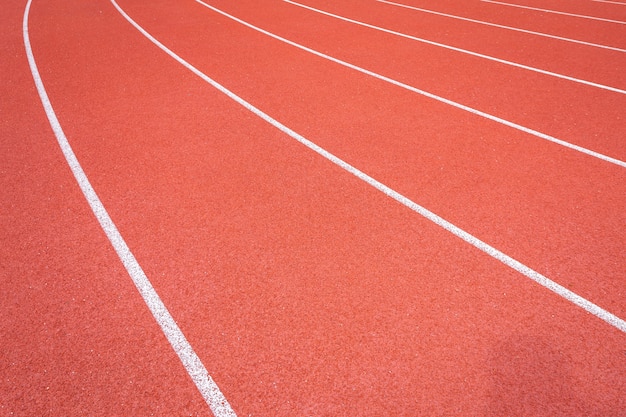 Linhas brancas de estádio e textura de pistas de borracha vermelha de pista de corrida em execução