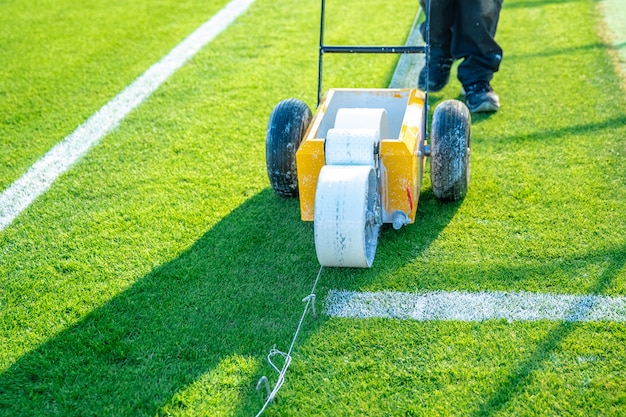 Linhas brancas desenhadas no campo de futebol com tinta branca na grama usando uma máquina especial antes de um jogo