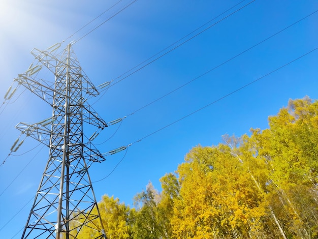 Linhas de energia e uma torre contra um fundo de céu azul um sol no outono