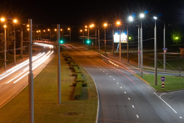 Linhas de luz da cidade noturna de carros carros na estrada com movimento desfocado Vista de rua da cidade moderna à noite Muita luz dos faróis dos carros, banners publicitários e luzes noturnas