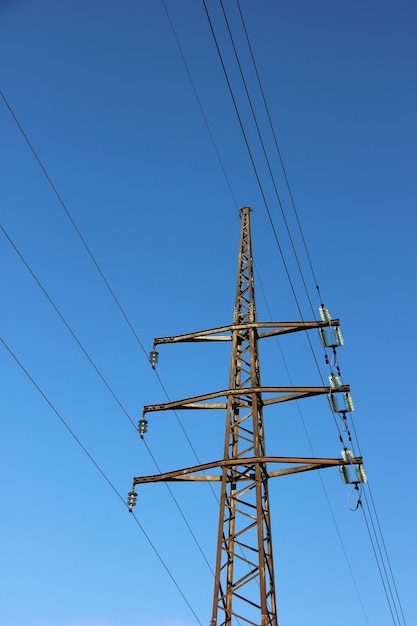 Linhas elétricas da confiança com os cabos no fundo do céu azul com nuvens.